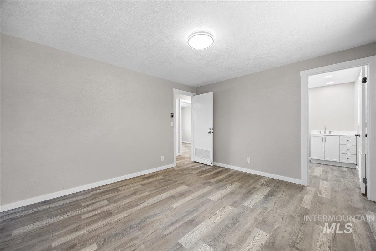 Unfurnished bedroom featuring wood finished floors, a textured ceiling, and ensuite bathroom