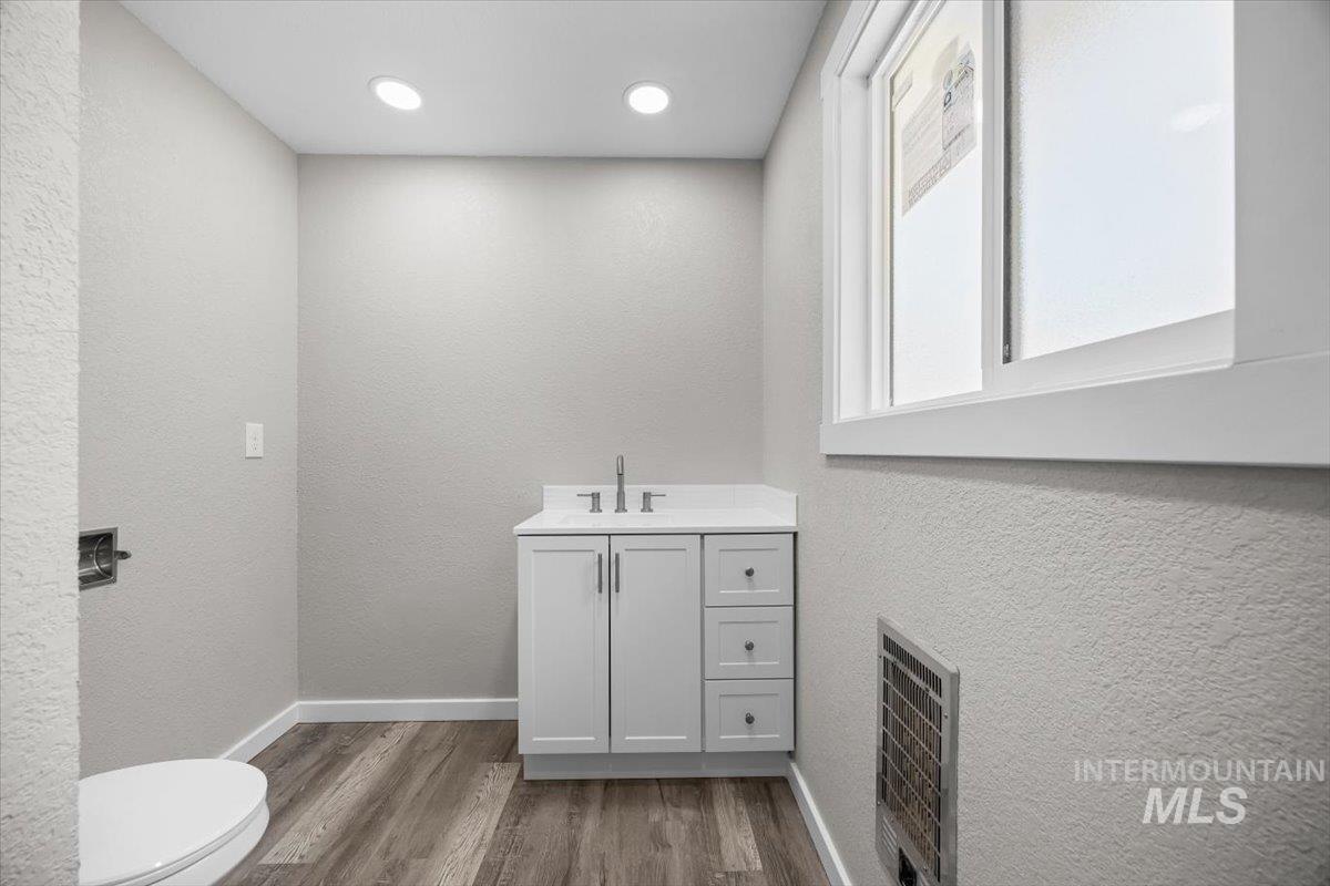 Bathroom featuring a textured wall, wood finished floors, vanity, and recessed lighting