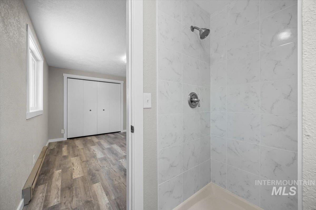 Bathroom featuring tiled shower and wood finished floors