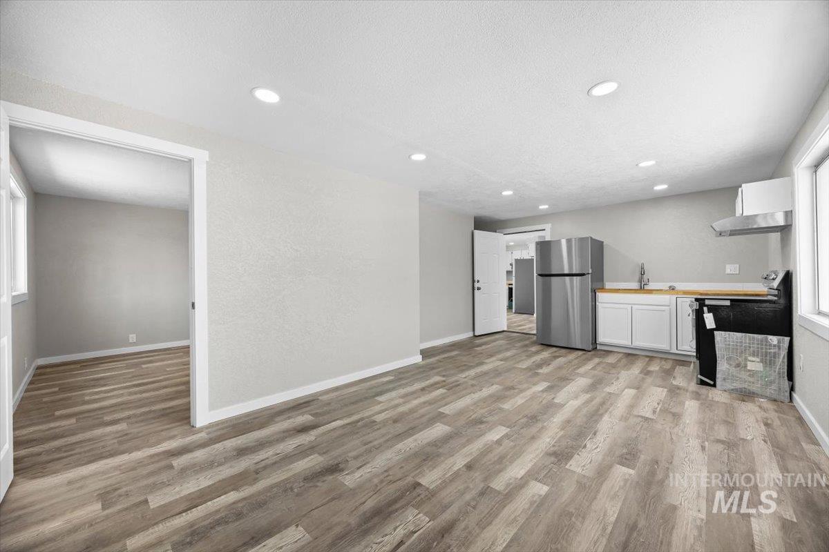 Kitchen featuring freestanding refrigerator, light wood-style flooring, electric range oven, white cabinets, and recessed lighting
