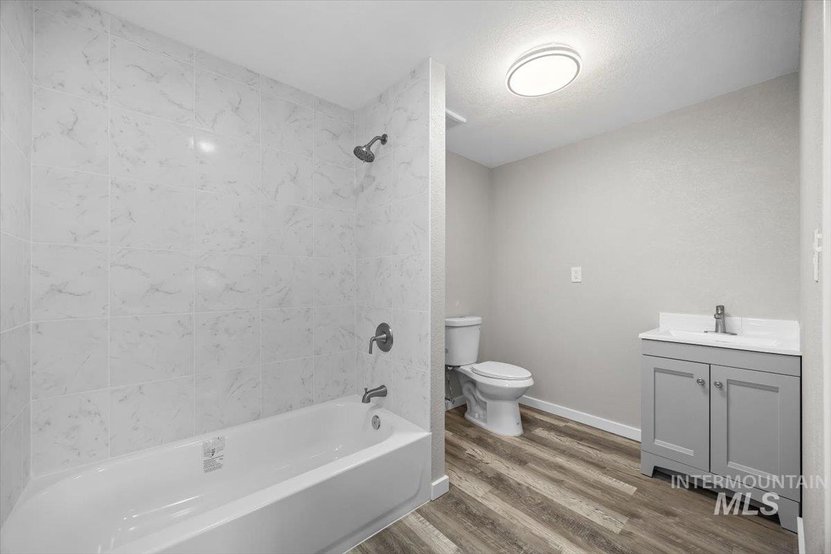 Full bath featuring vanity, wood finished floors, bathtub / shower combination, and a textured ceiling