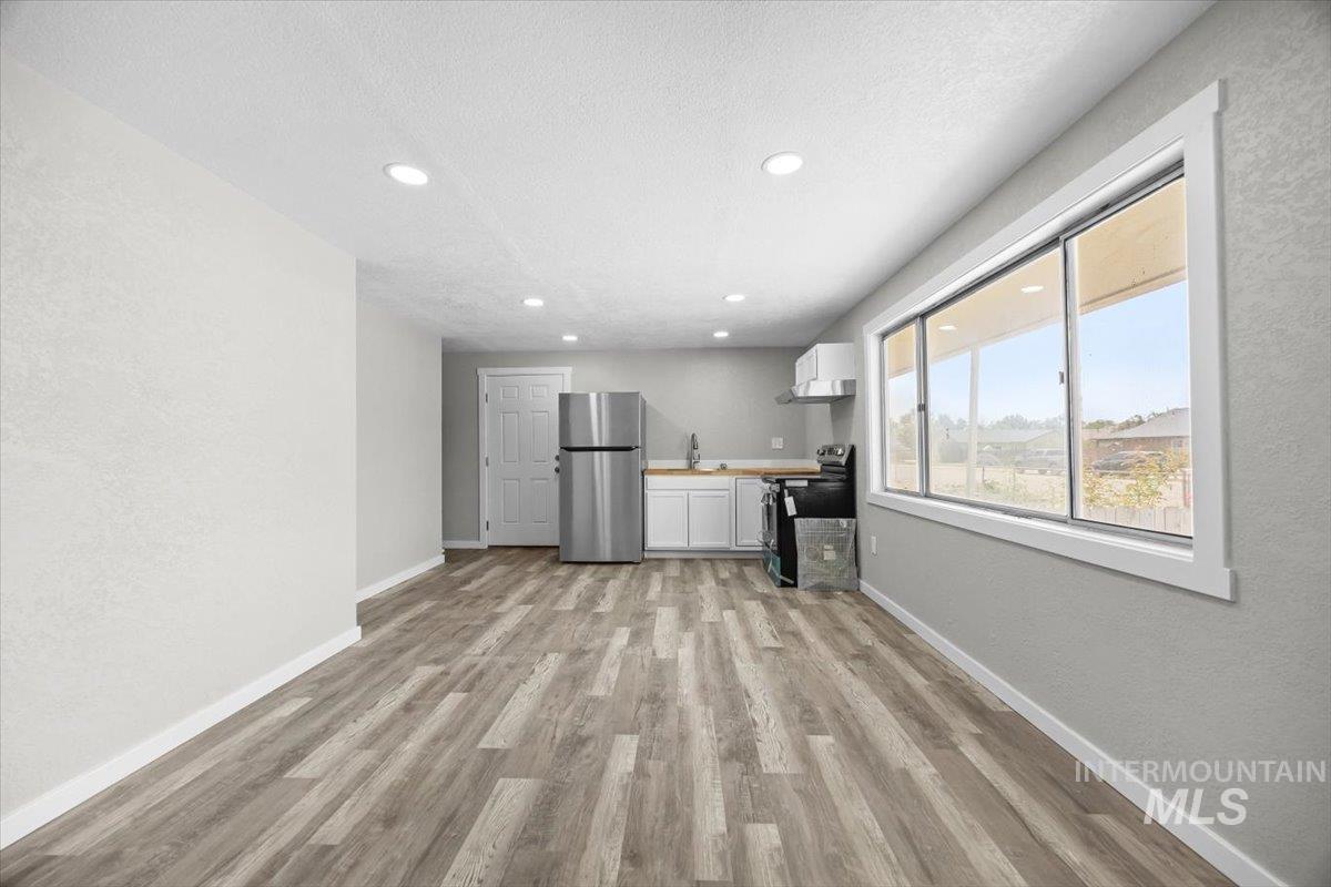 Unfurnished living room with light wood-style floors, recessed lighting, a textured wall, and a textured ceiling