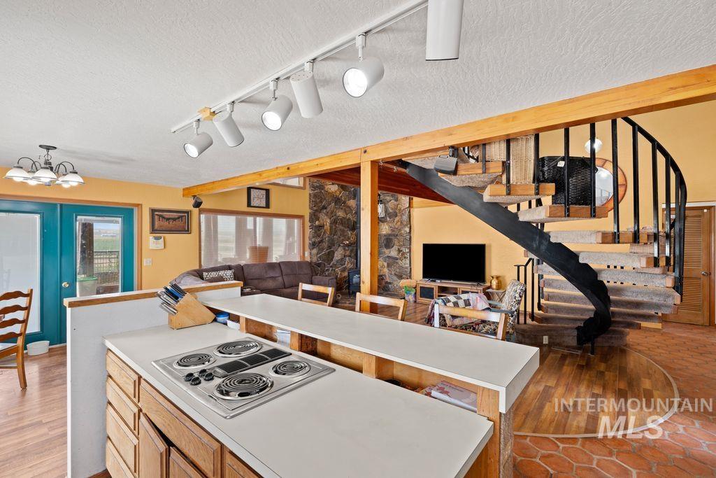 Kitchen featuring a textured ceiling, stainless steel electric stovetop, a kitchen island, light wood finished floors, and open floor plan