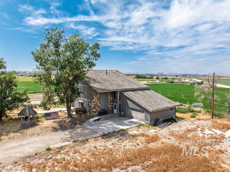 Rear view of property featuring concrete driveway, a garage, and a view of countryside
