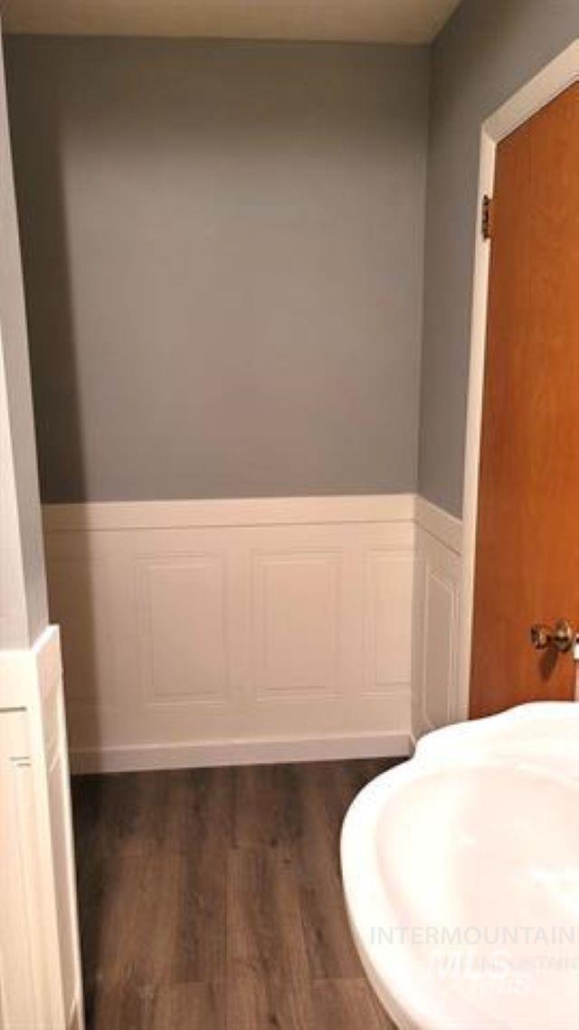 Bathroom with wood finished floors, a wainscoted wall, and a decorative wall