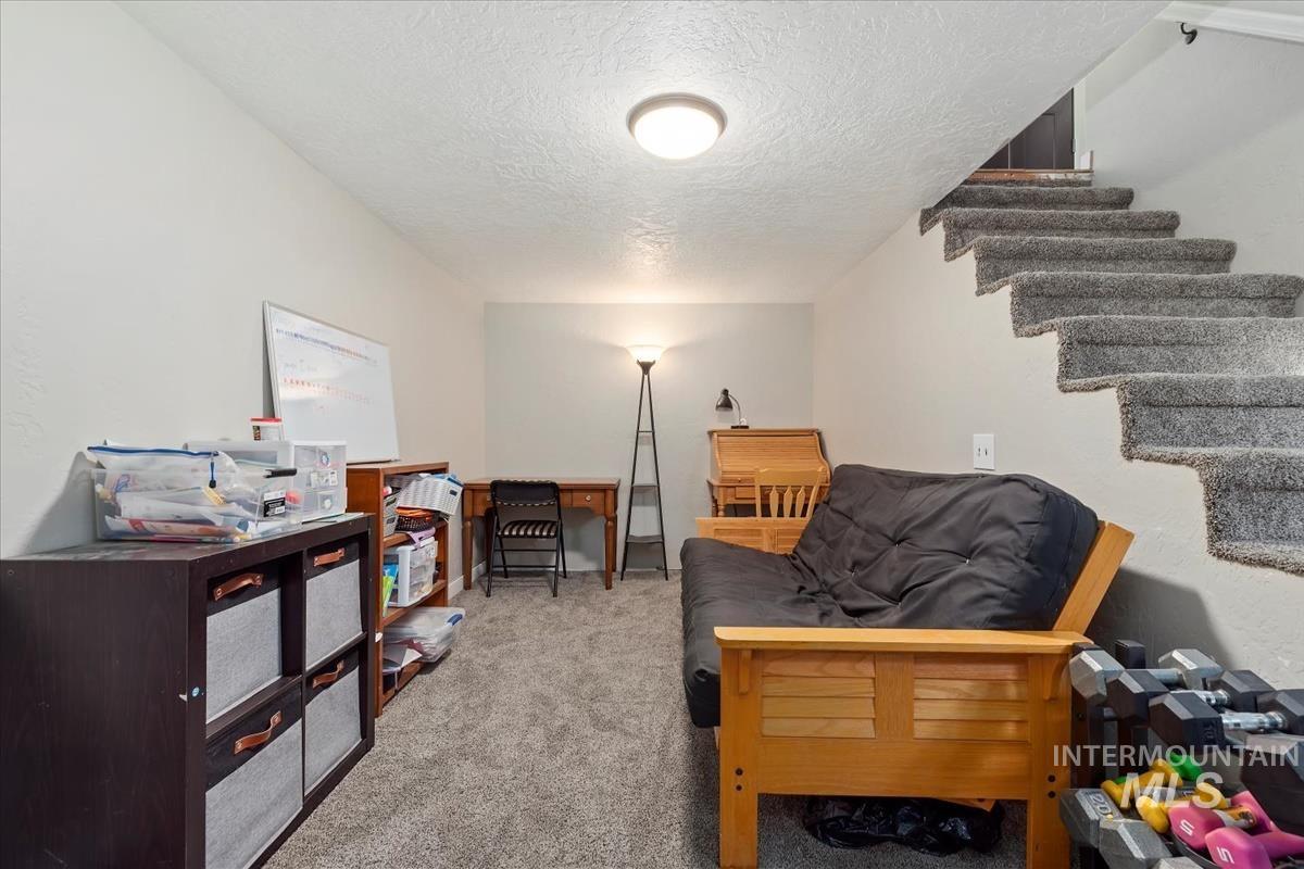 Sitting room with carpet, a textured ceiling, and stairs