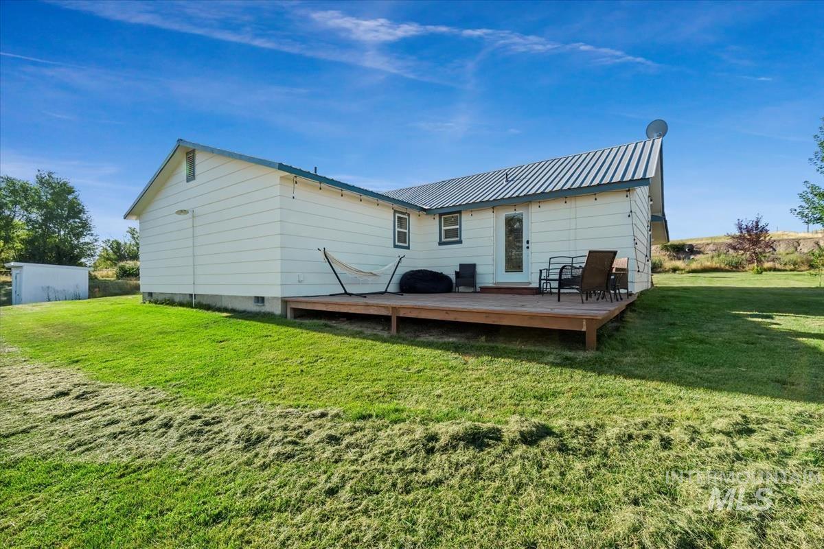Rear view of property with a metal roof, a yard, and a wooden deck