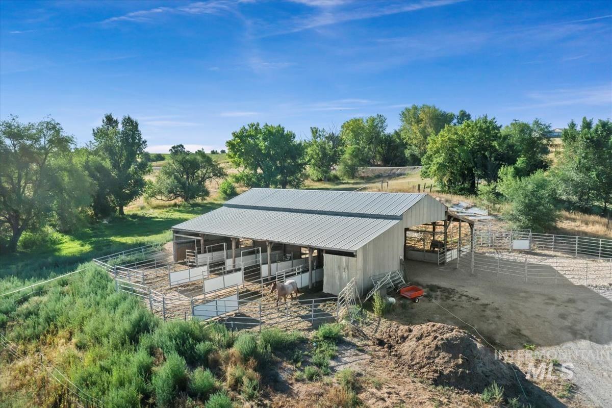 Rear view of house with an exterior structure, a metal roof, an outbuilding, a view of countryside, and view of wooded area