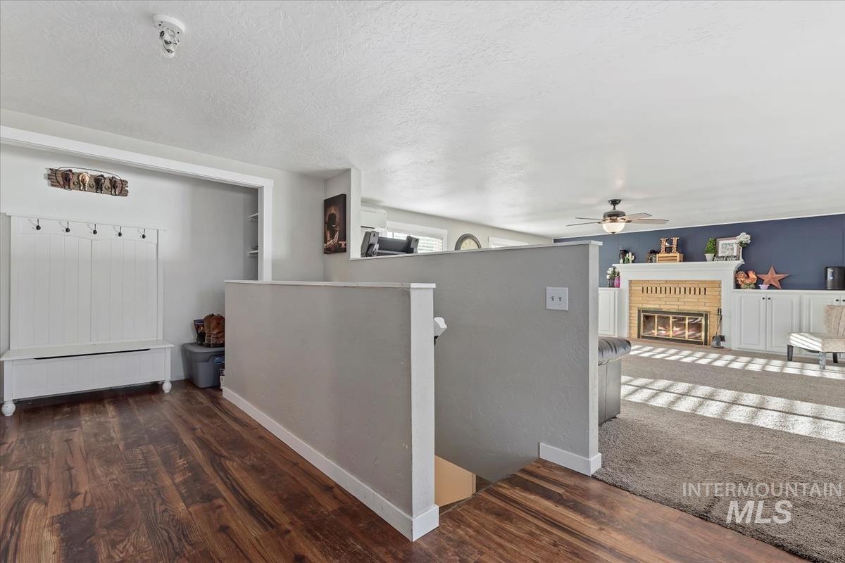 Corridor featuring a textured ceiling, wood finished floors, an upstairs landing, and a baseboard radiator