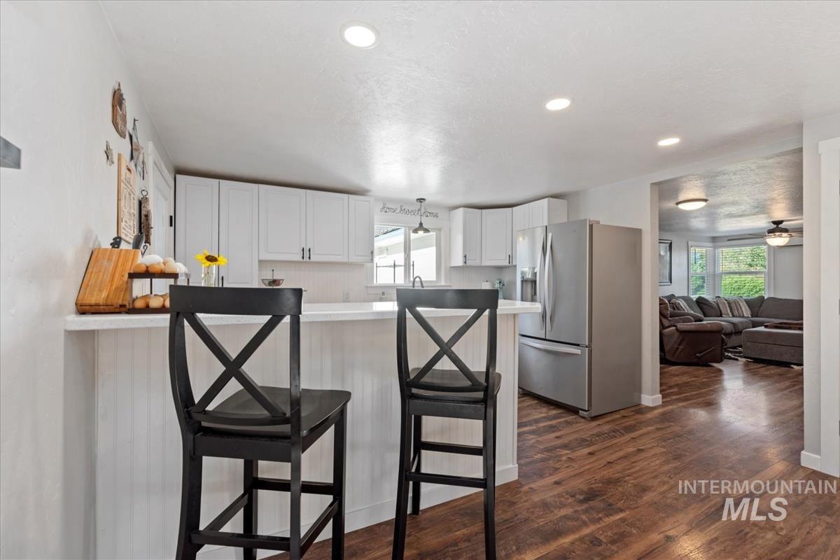 Kitchen with stainless steel refrigerator with ice dispenser, plenty of natural light, a kitchen bar, white cabinetry, and recessed lighting