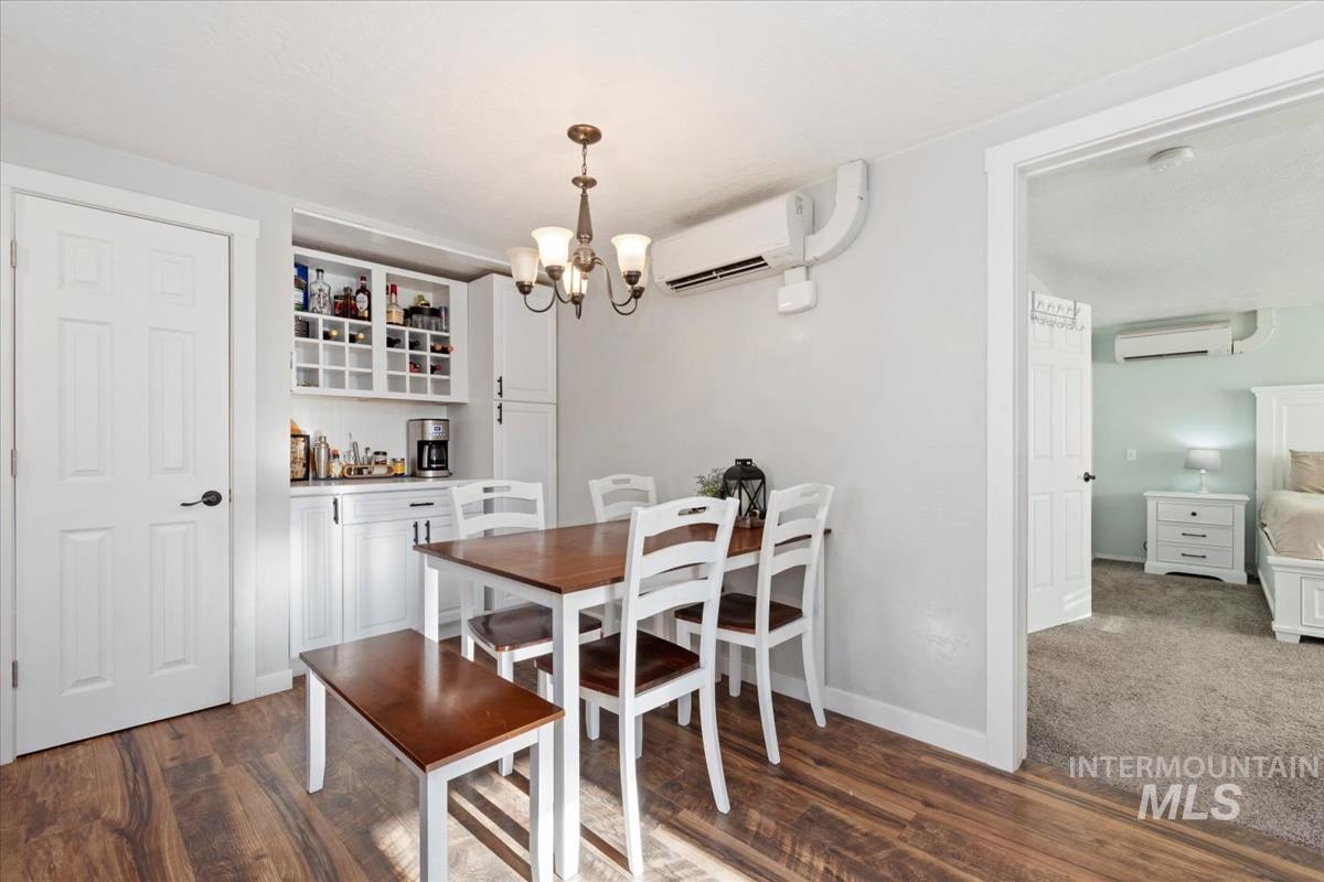 Dining room with a chandelier, dark wood-type flooring, a wall mounted air conditioner, and a wall mounted AC