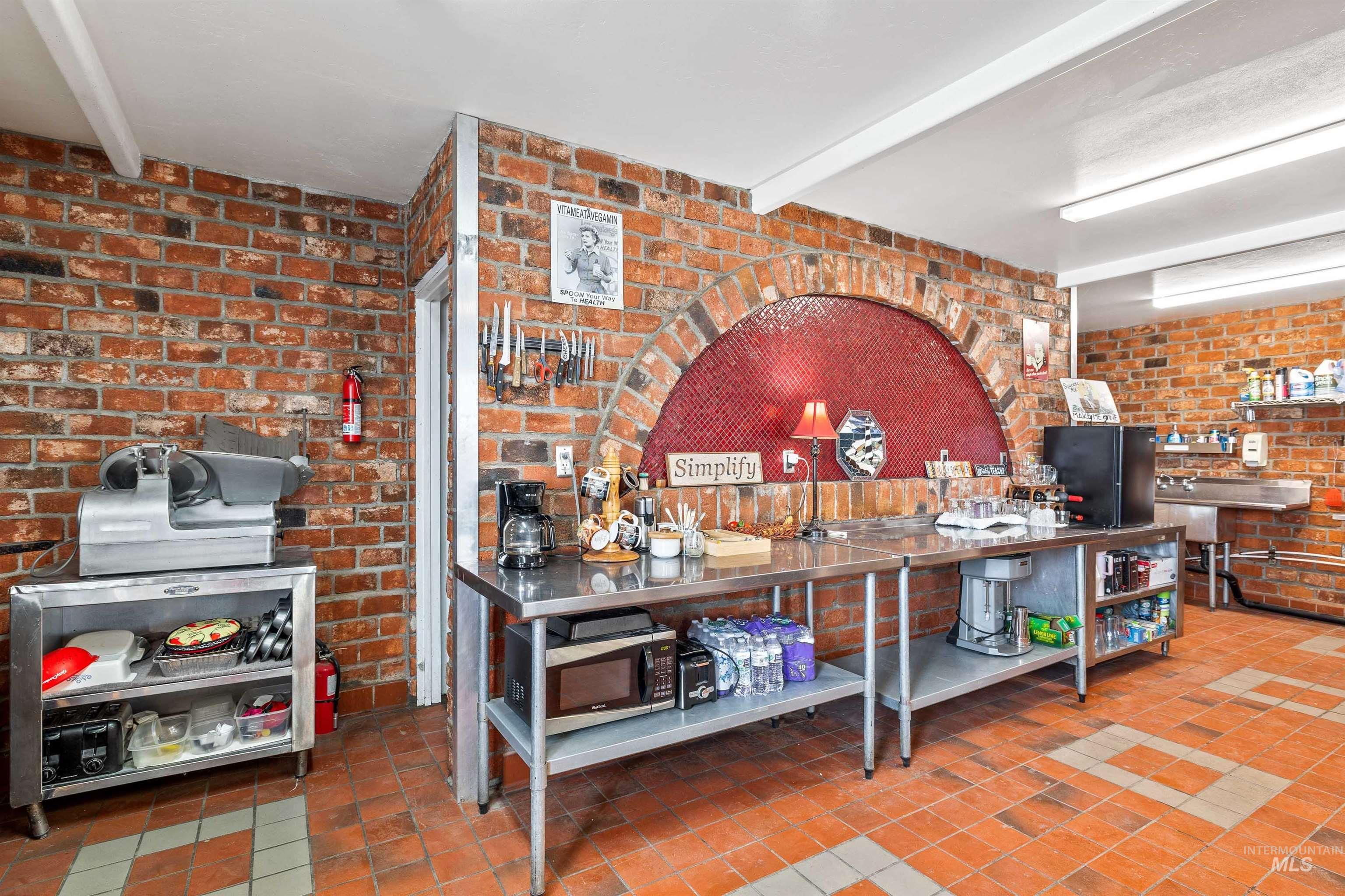 Misc room featuring beam ceiling, brick wall, and tile patterned flooring