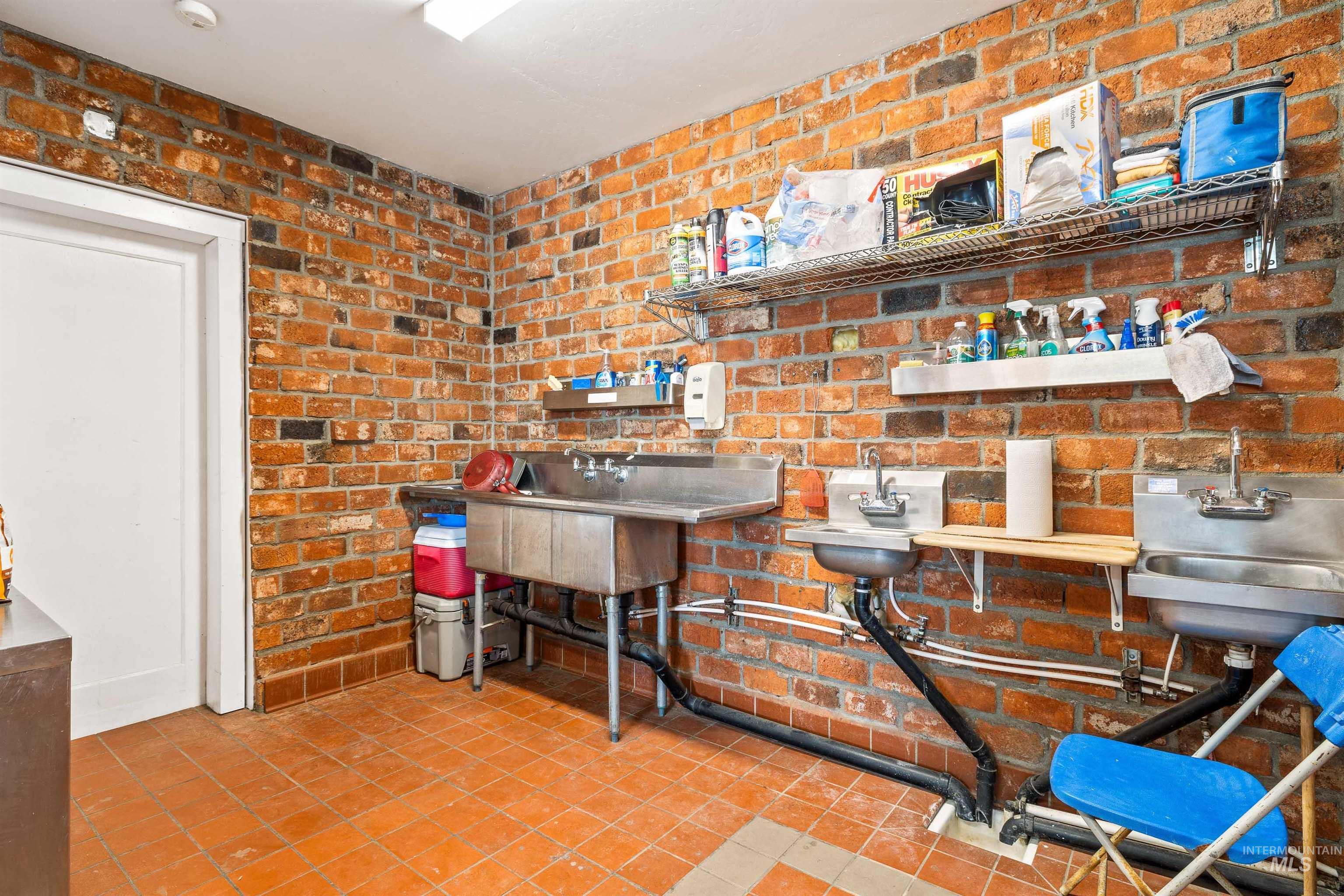 Kitchen featuring light tile patterned flooring and brick wall