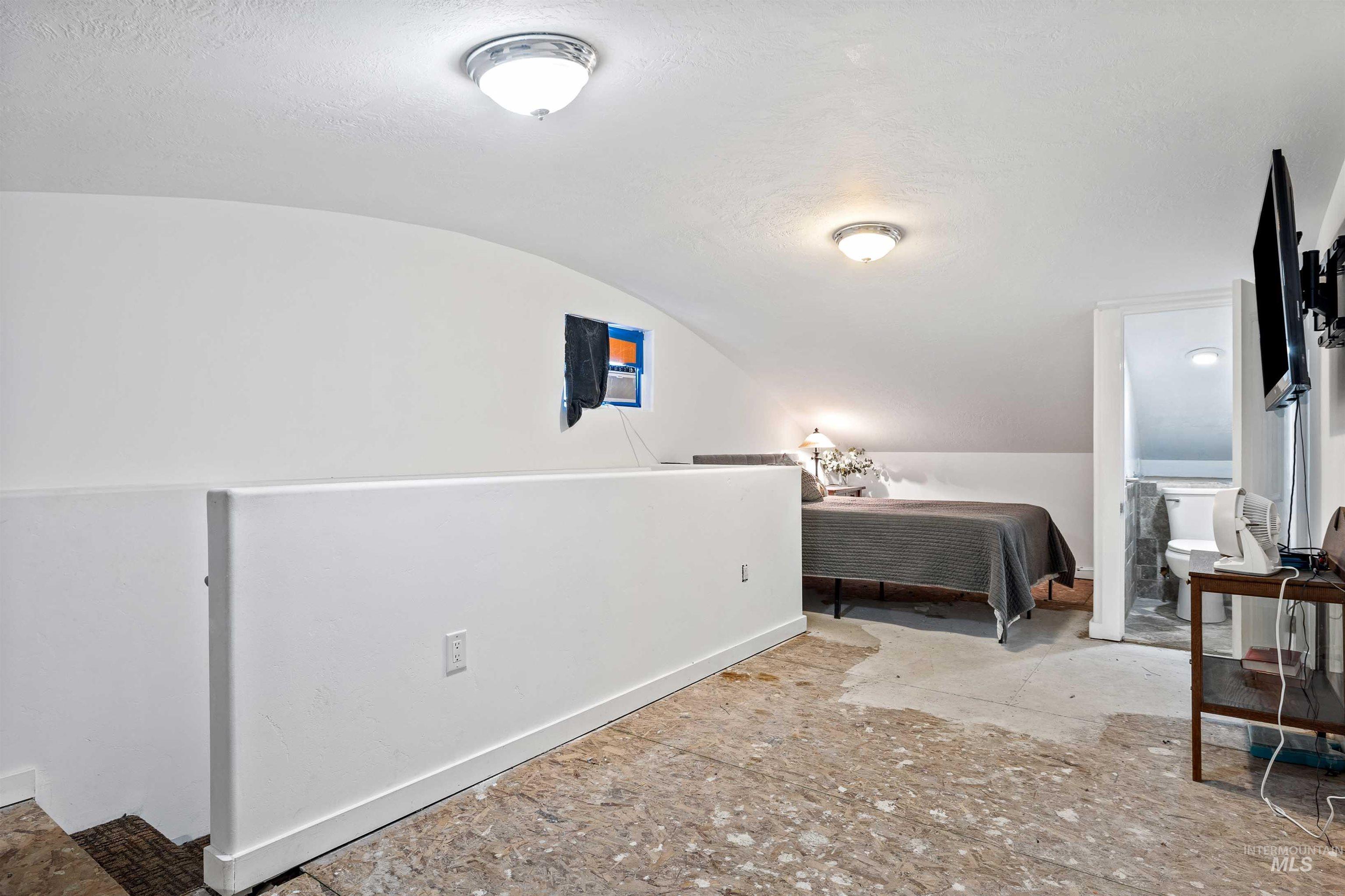 Bedroom featuring vaulted ceiling and a textured ceiling