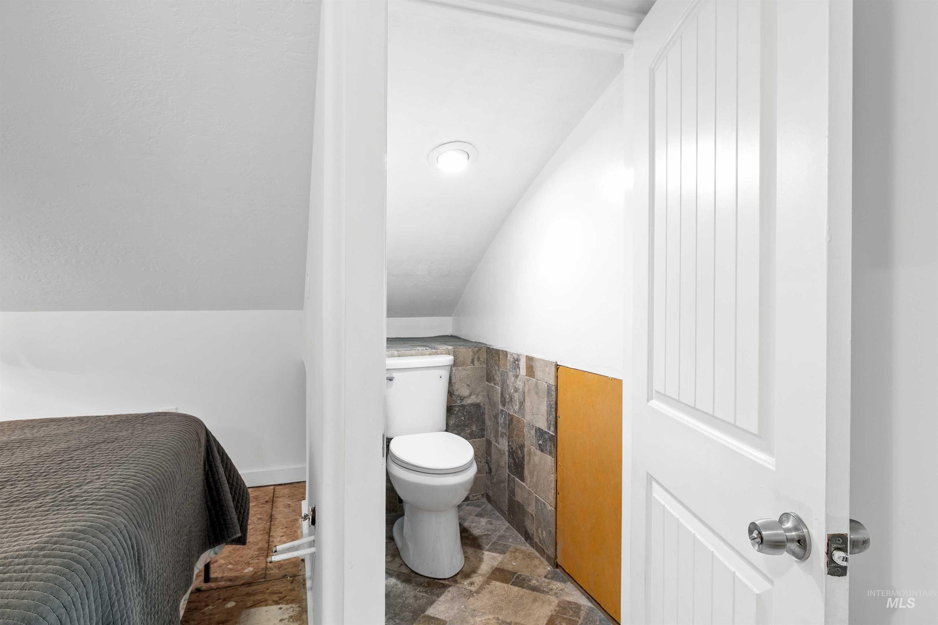 Bathroom featuring stone finish floors and vaulted ceiling