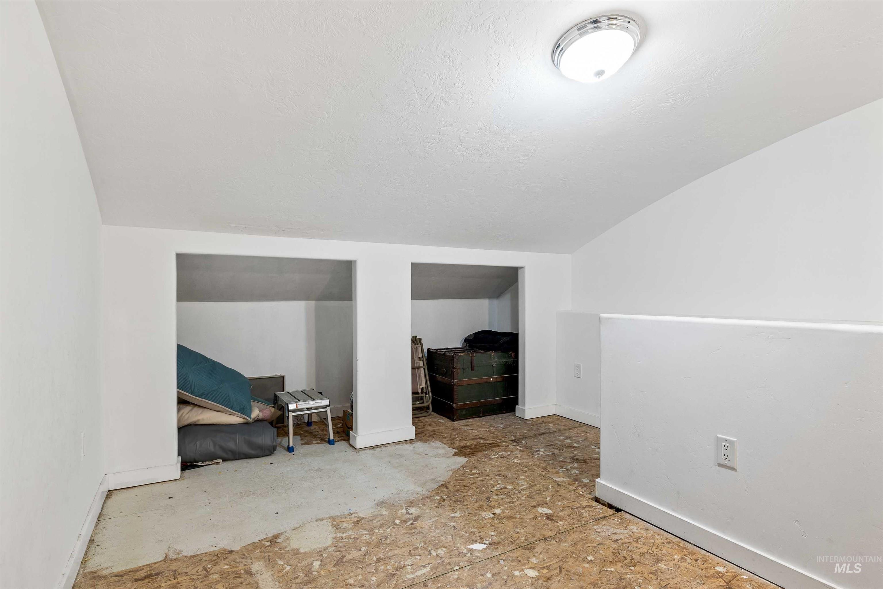 Additional living space featuring a textured ceiling and vaulted ceiling