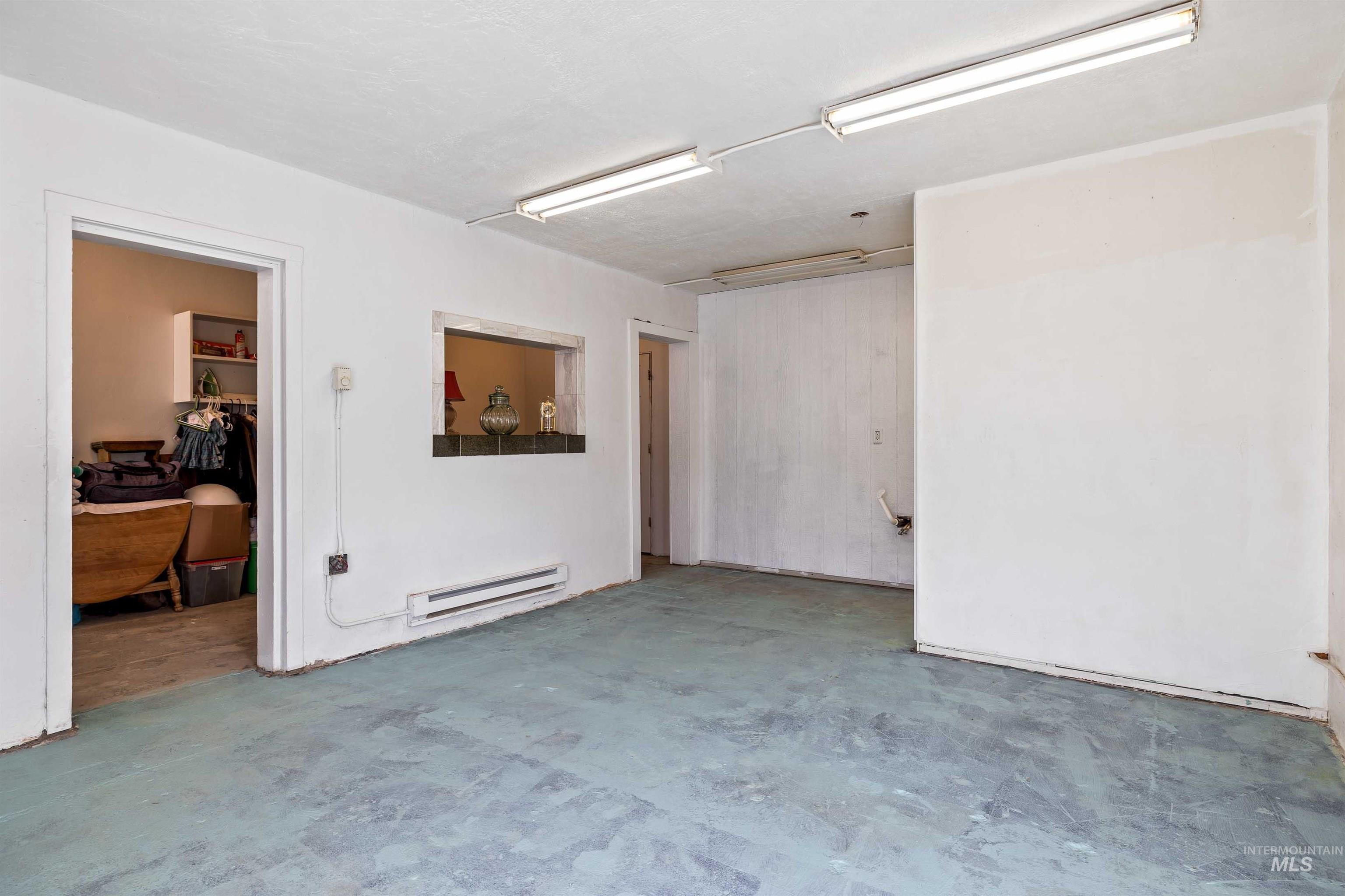 Empty room featuring a baseboard heating unit and concrete flooring