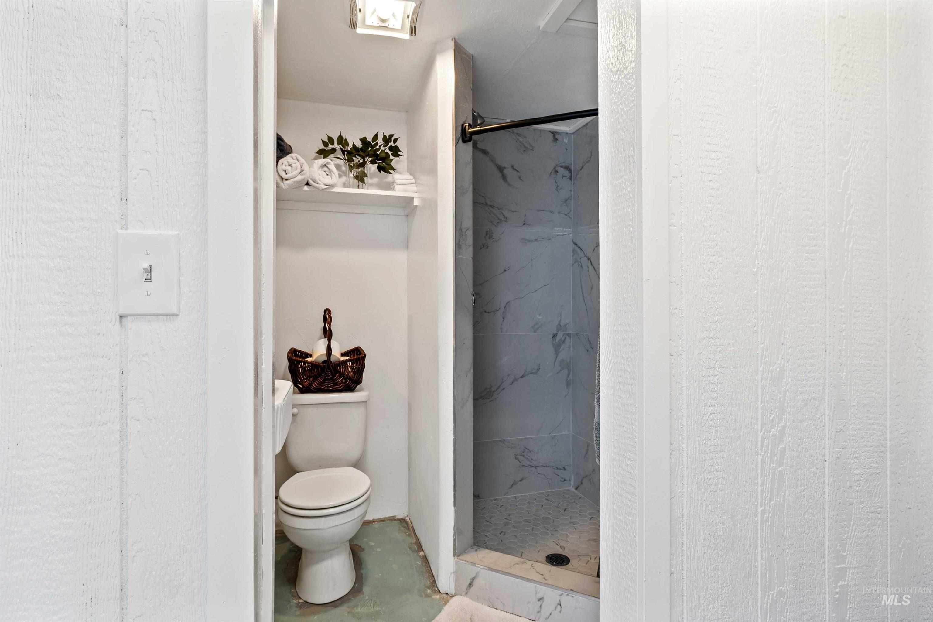 Full bath featuring a marble finish shower and toilet