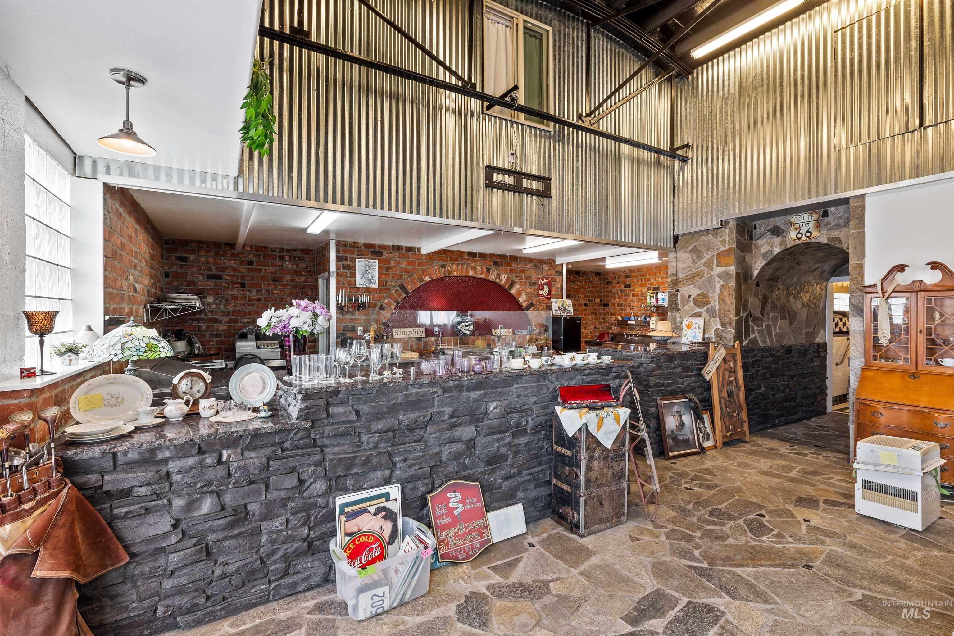 Kitchen featuring a high ceiling, stone flooring, and brick wall
