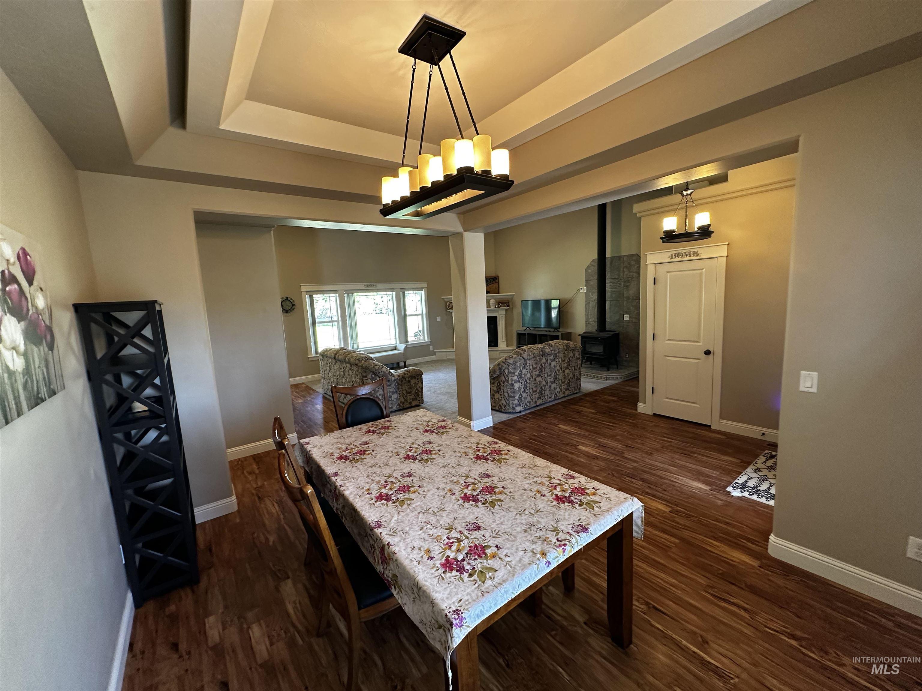 Dining space with a raised ceiling and dark wood-style flooring