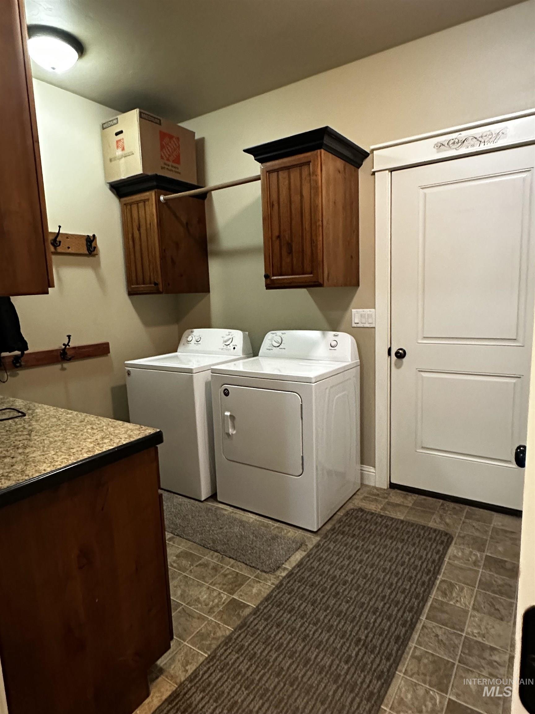 Washroom featuring cabinet space, washing machine and dryer, and stone finish flooring