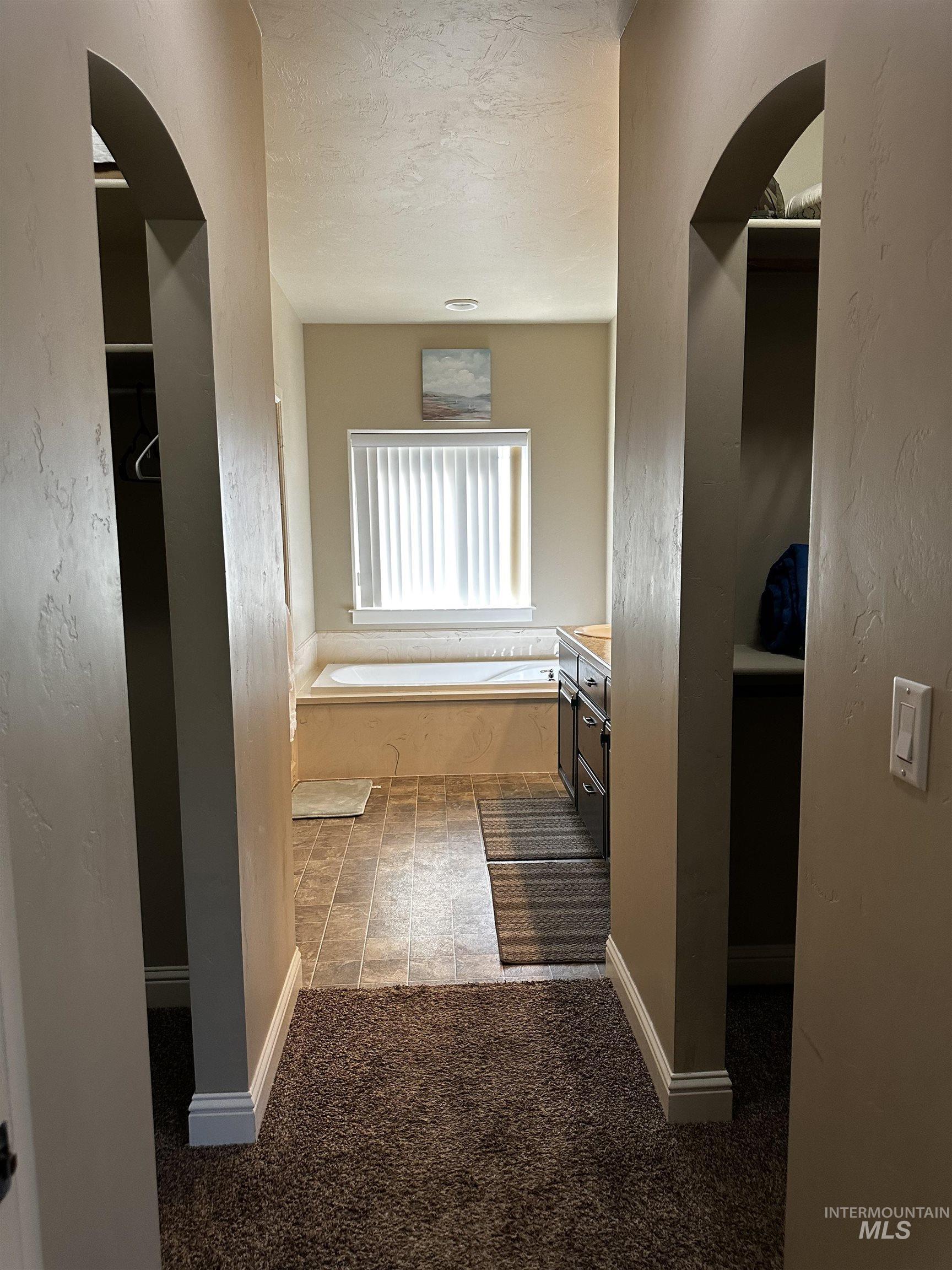 Bathroom featuring a bath, vanity, a textured ceiling, a textured wall, and a closet