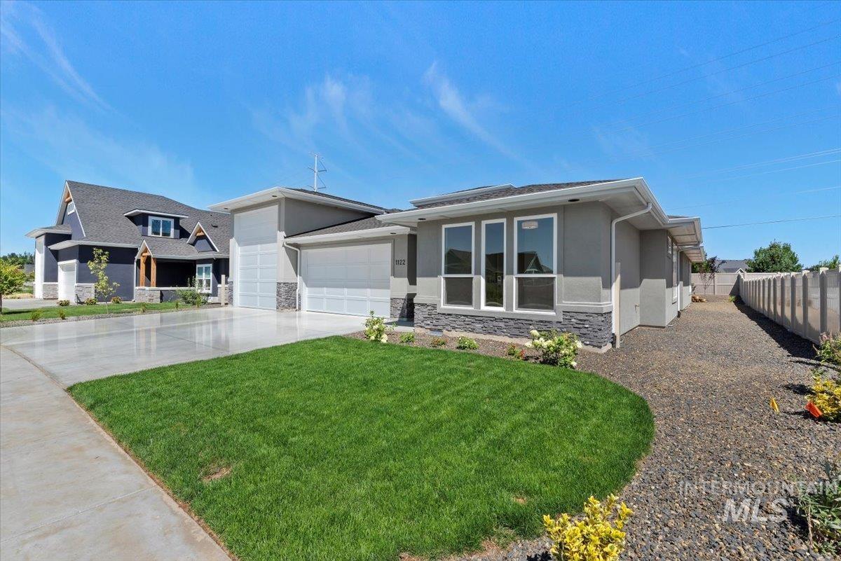 View of front of home featuring stone siding, stucco siding, an attached garage, driveway, and a front yard