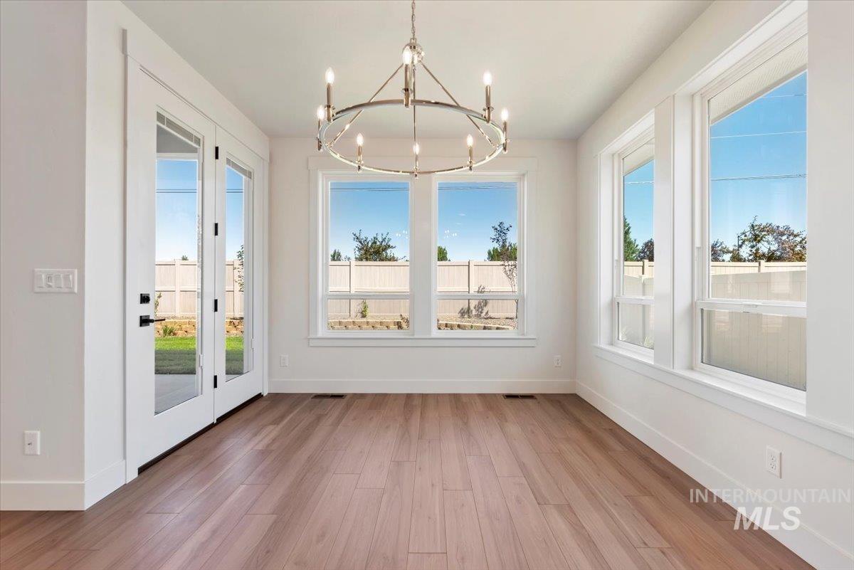 Unfurnished dining area with light wood-style floors, healthy amount of natural light, and a chandelier