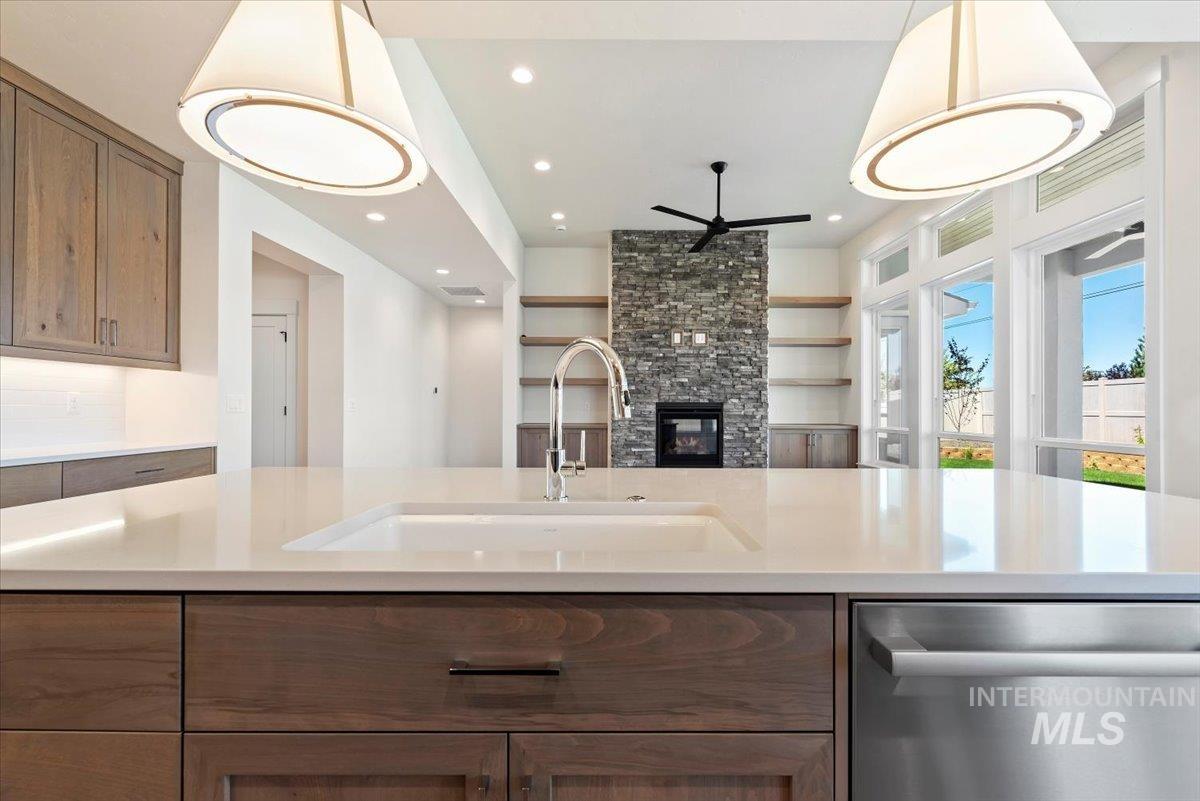 Kitchen with stainless steel dishwasher, brown cabinetry, pendant lighting, a ceiling fan, and open floor plan