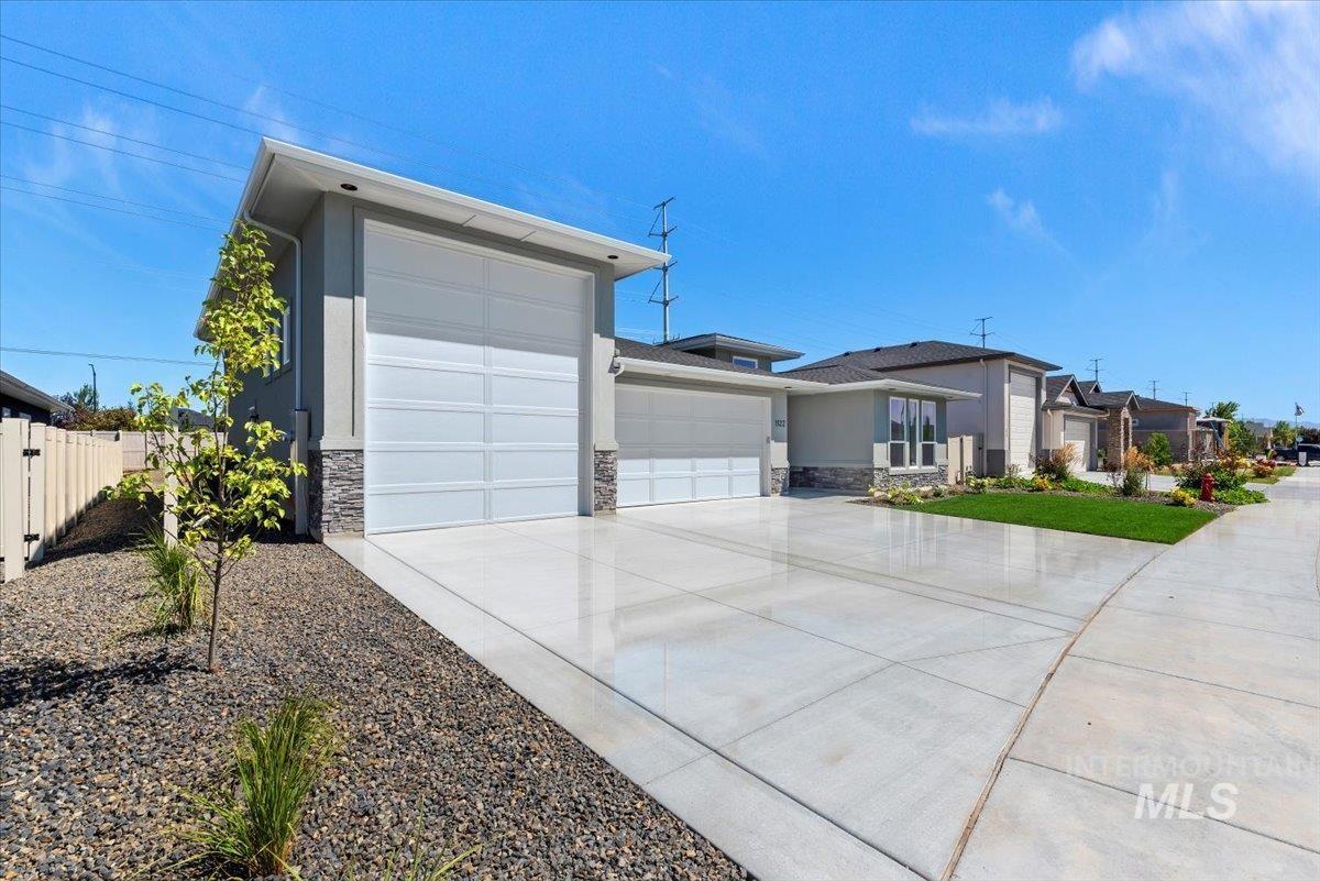 View of front facade with an attached garage, stone siding, concrete driveway, and stucco siding