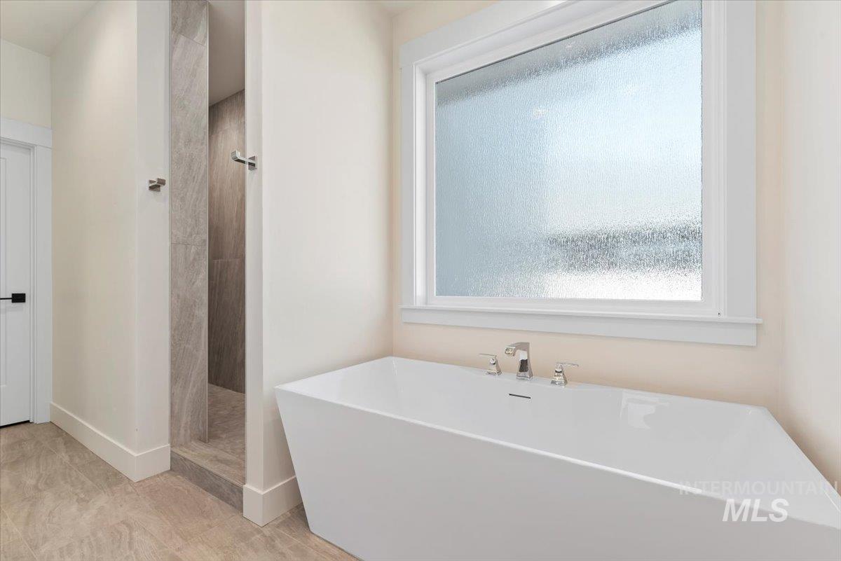 Bathroom with a shower stall, a freestanding tub, and plenty of natural light
