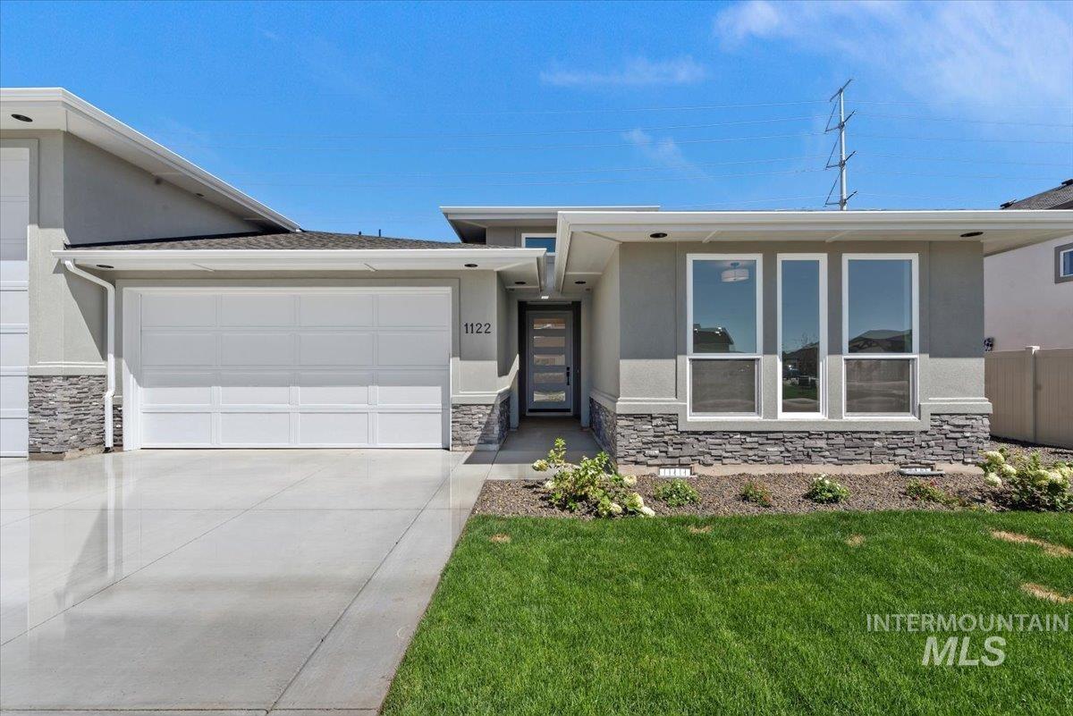 View of front of home featuring stone siding, an attached garage, stucco siding, and a front lawn