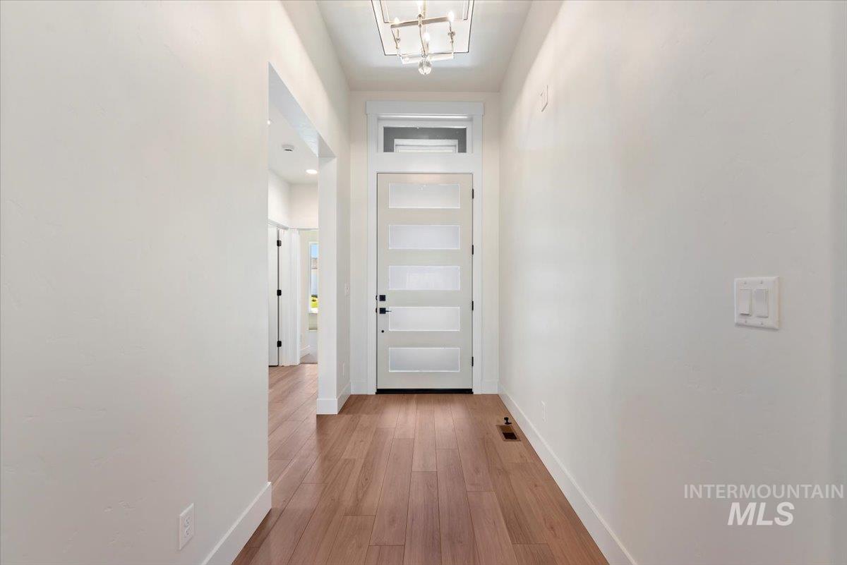 Hall featuring light wood finished floors and a chandelier