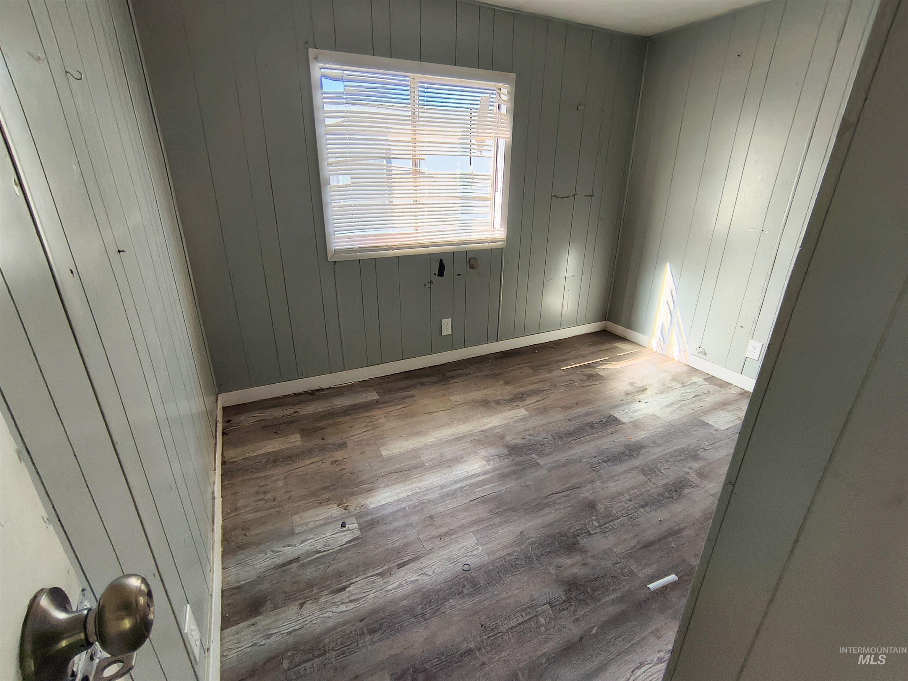 Spare room with wood finished floors and wooden walls