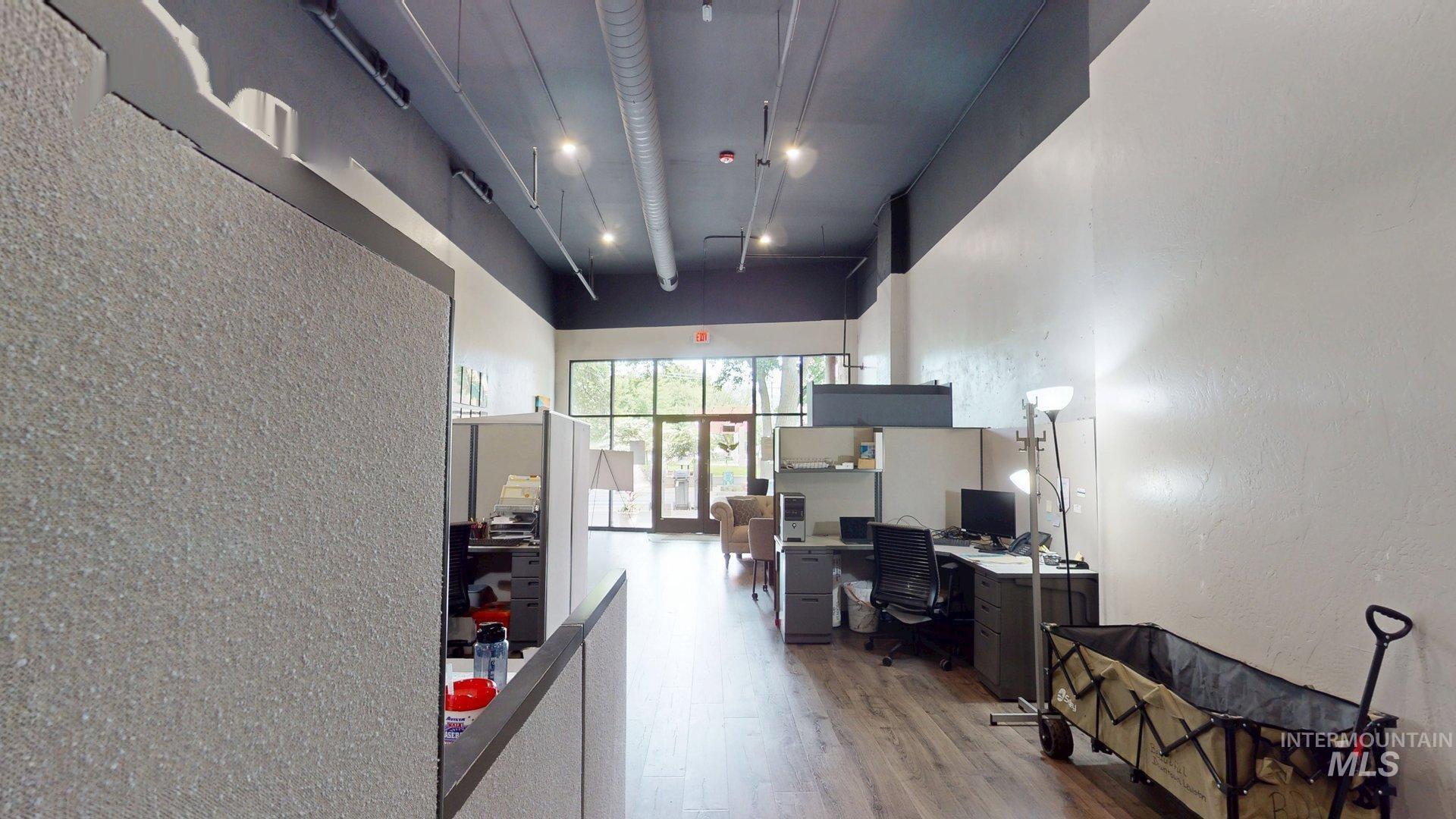 Office with a textured wall, wood finished floors, and a high ceiling