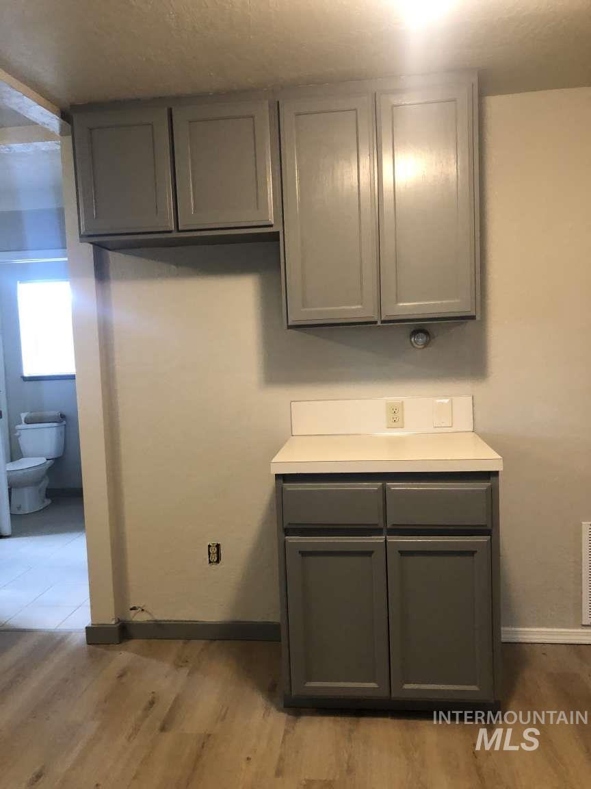 Kitchen featuring light countertops, gray cabinetry, and light wood-style flooring
