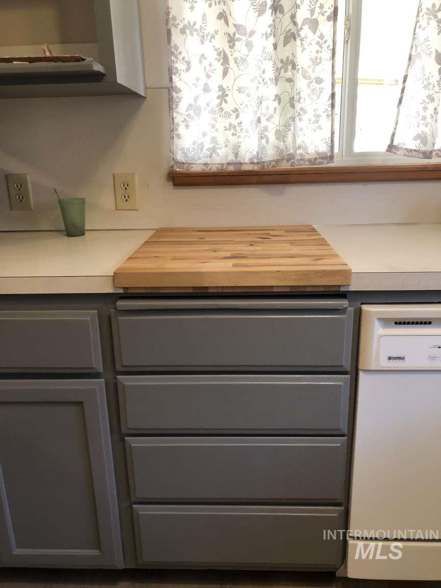Kitchen view of dishwasher, light countertops, and gray cabinetry