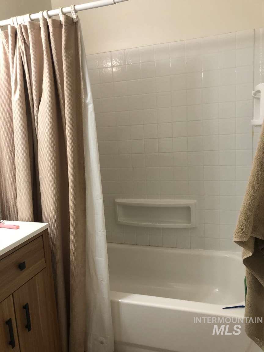 Full bath with shower / bath combo with shower curtain and vanity