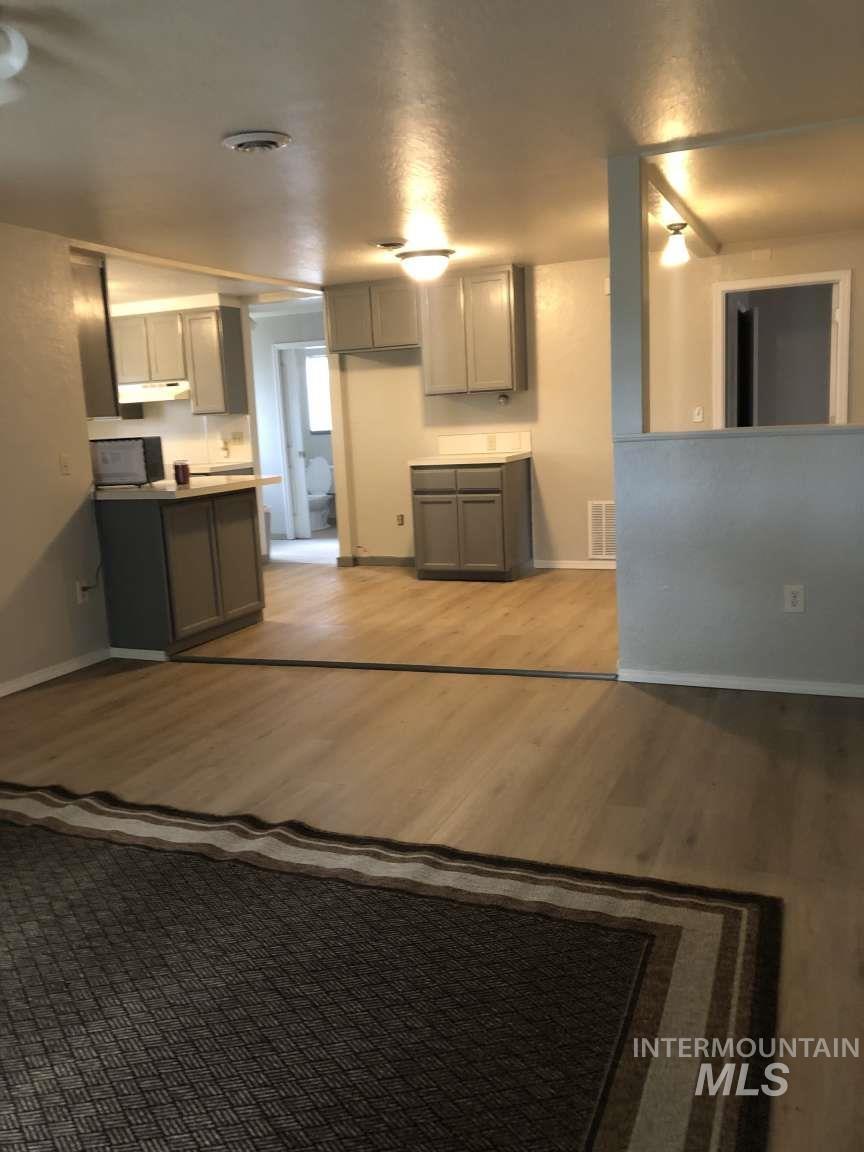 Kitchen featuring gray cabinetry, dark wood-style flooring, and under cabinet range hood