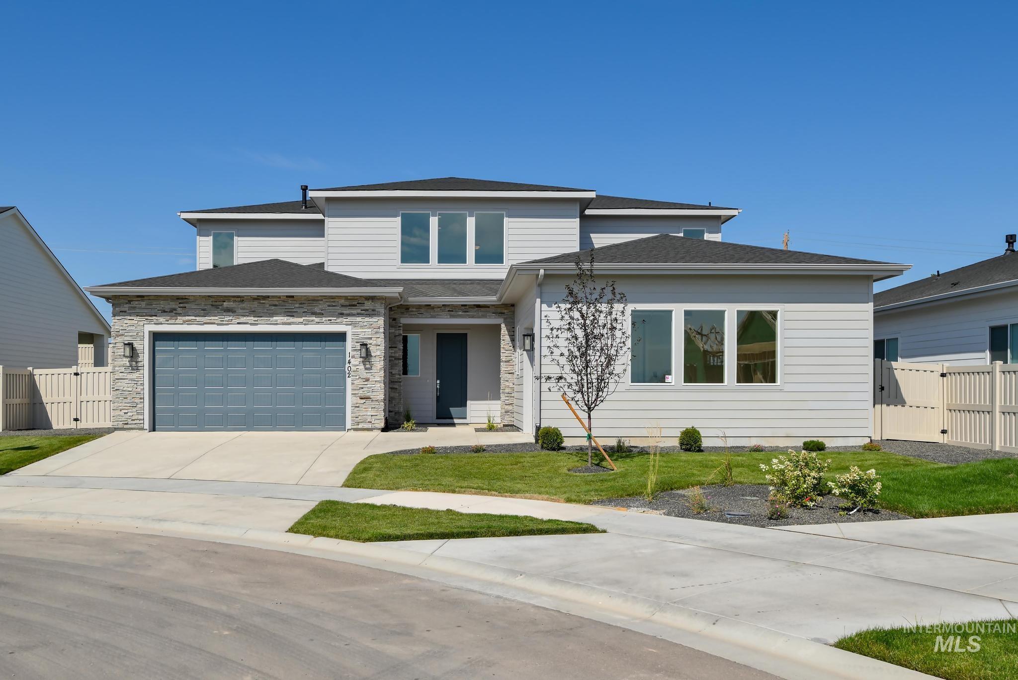 Prairie-style house with concrete driveway, stone siding, and roof with shingles