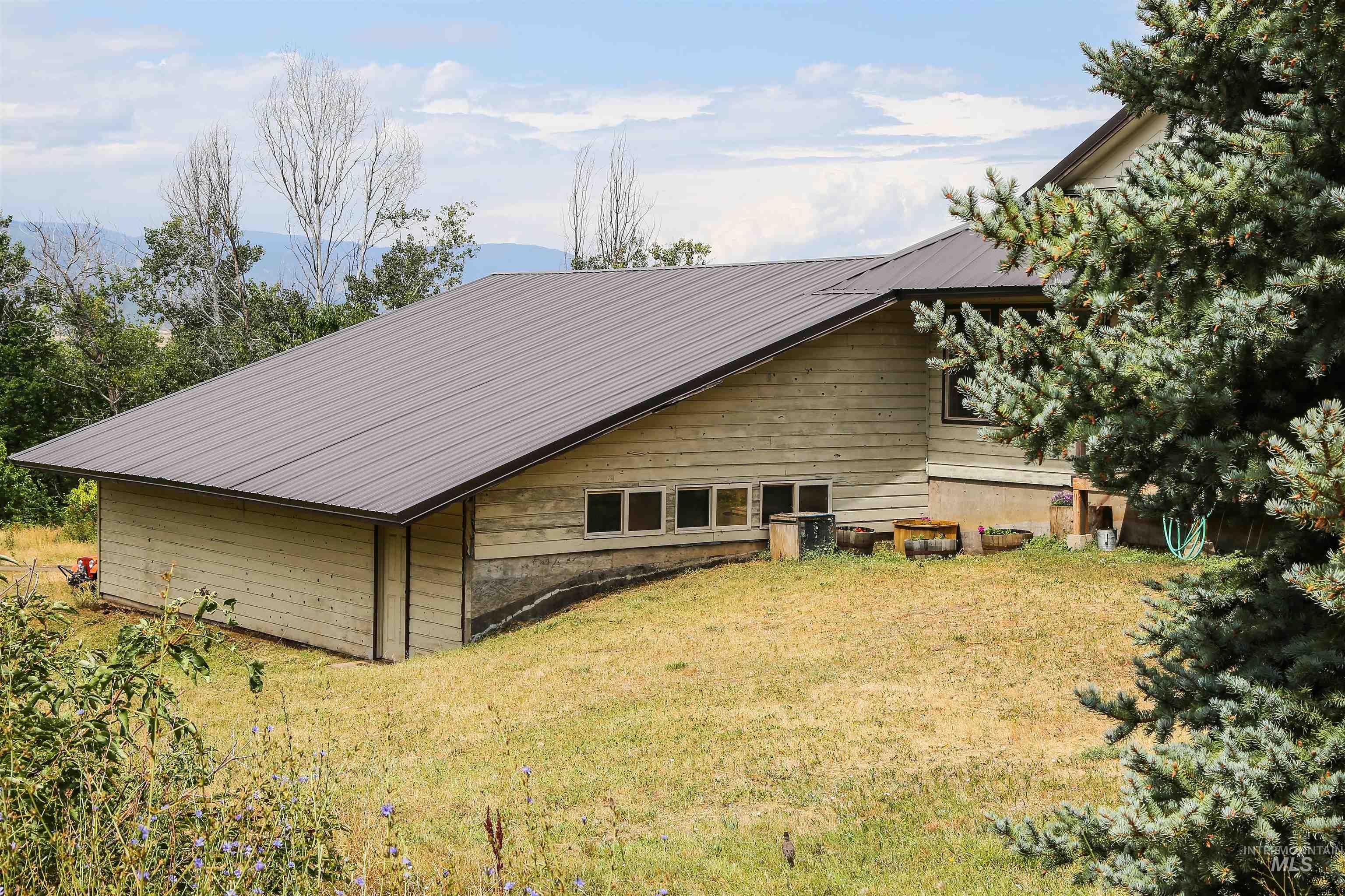 View of side of property with a lawn and a metal roof