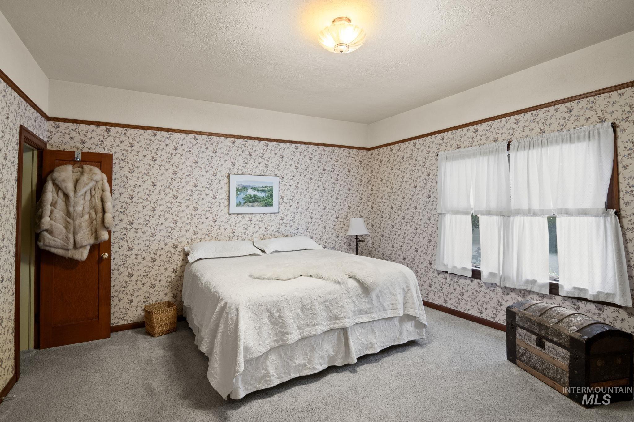 Carpeted bedroom with wallpapered walls and a textured ceiling