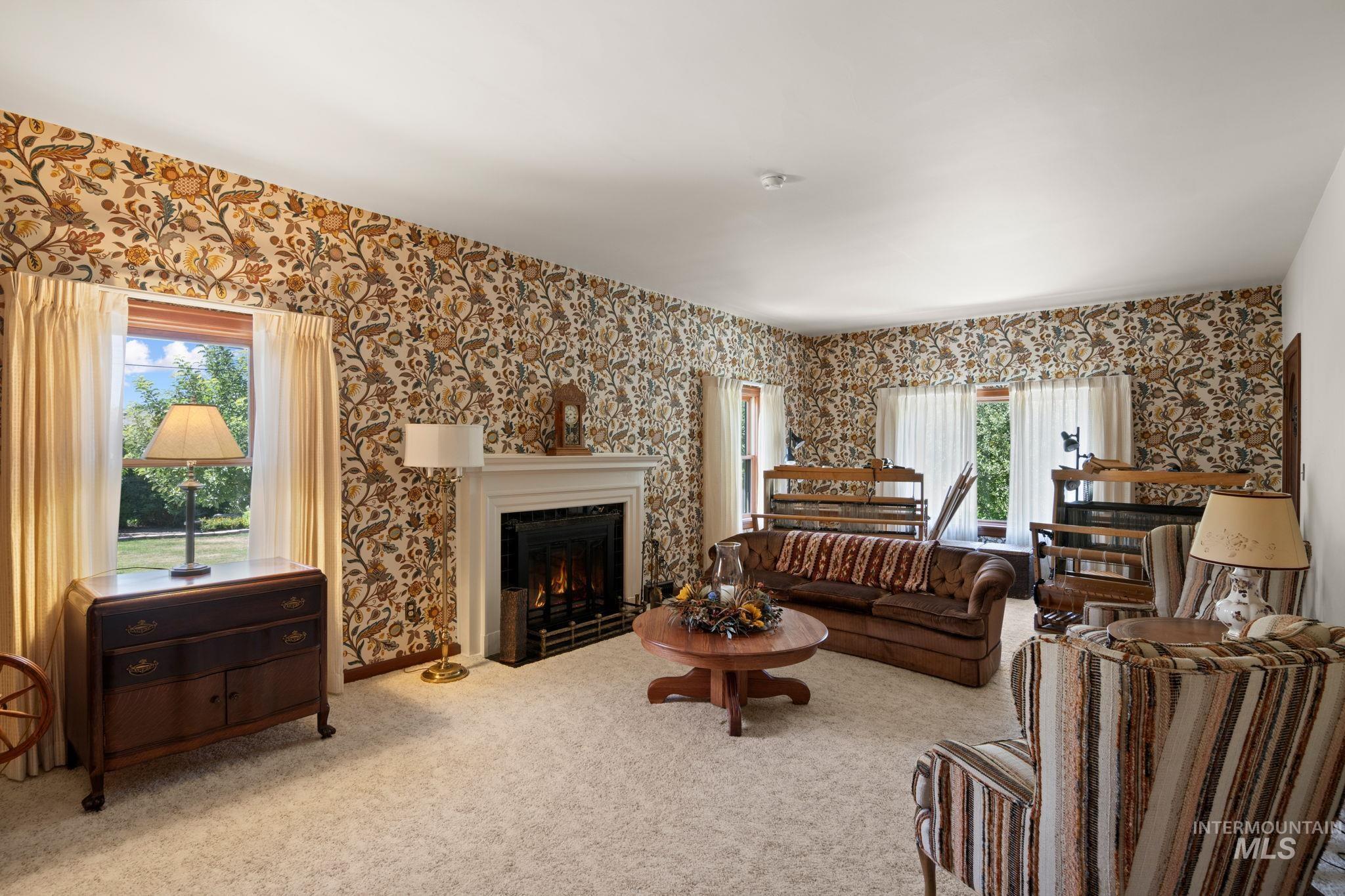 Carpeted living room featuring wallpapered walls and a warm lit fireplace