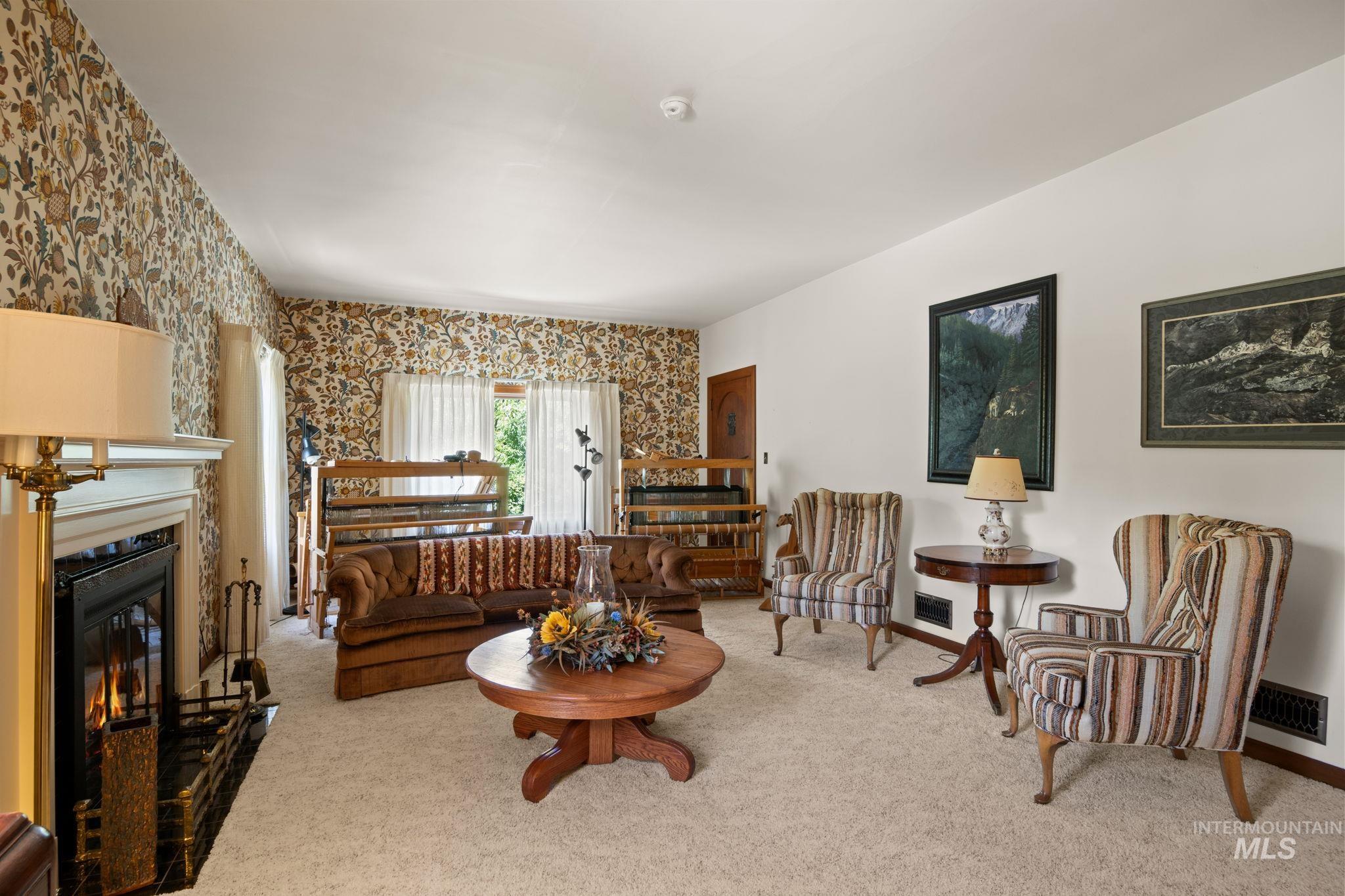 Carpeted living room featuring wallpapered walls and a glass covered fireplace