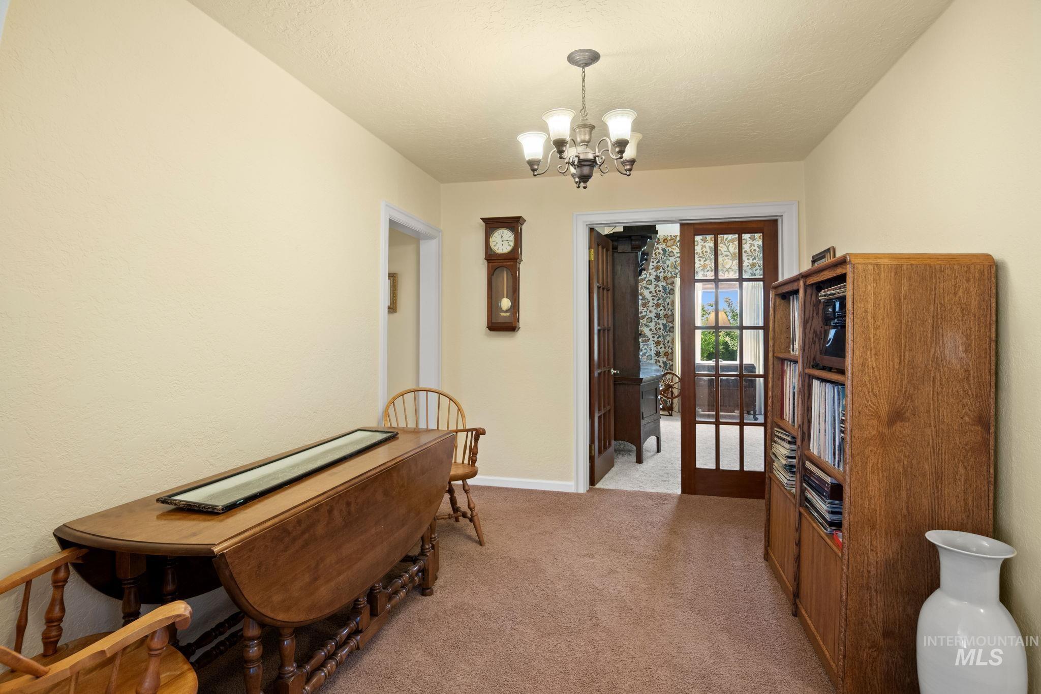 Sitting room with light colored carpet, a chandelier, and a textured ceiling