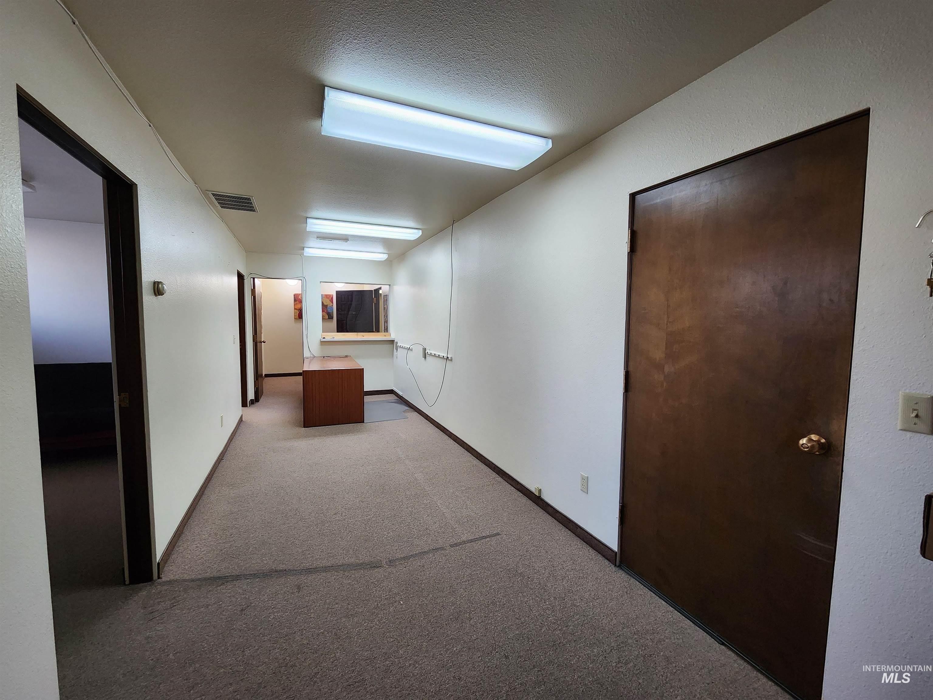 Corridor with light carpet and a textured ceiling