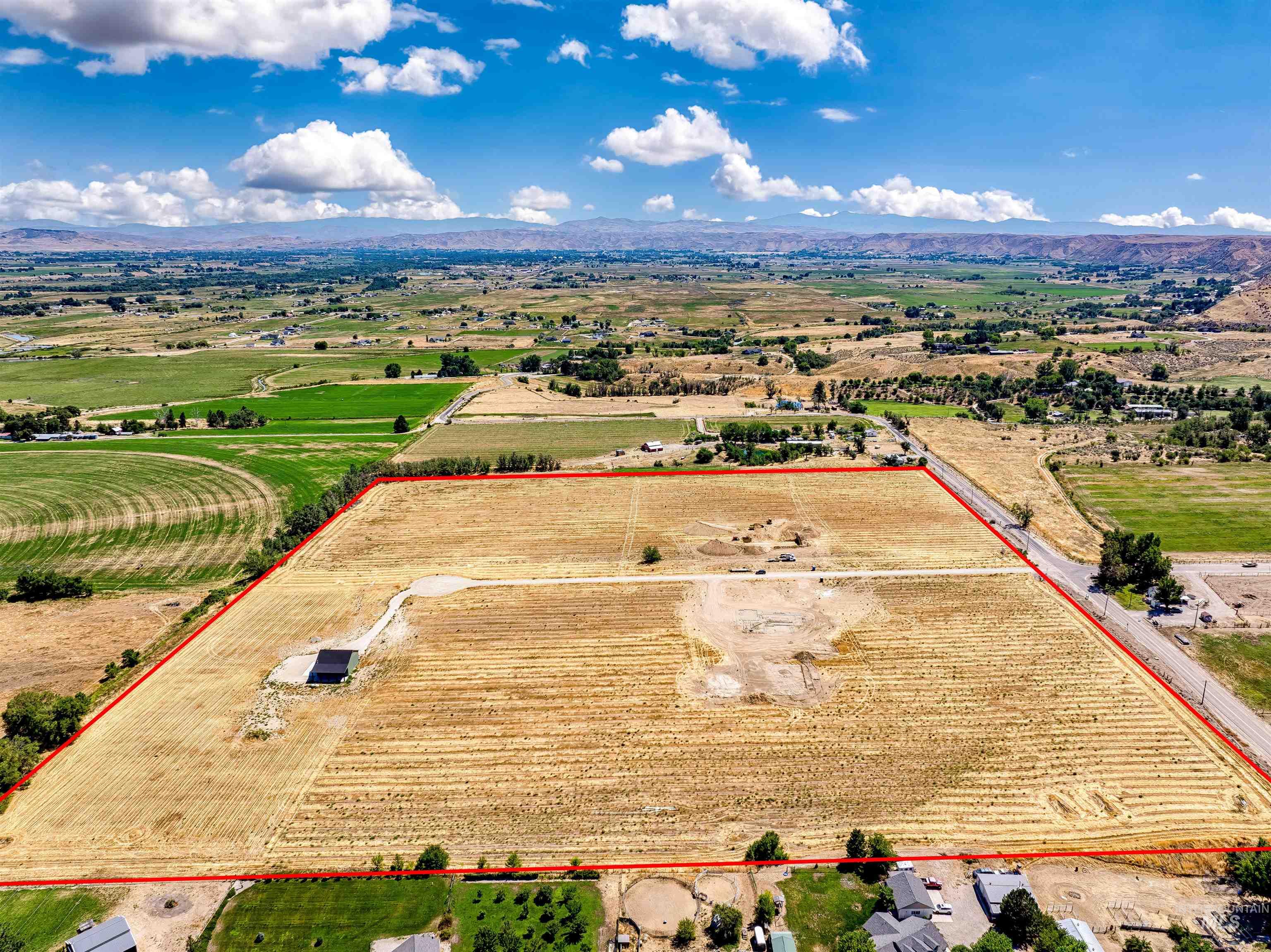 Aerial view of sparsely populated area with property parcel outlined and mountains