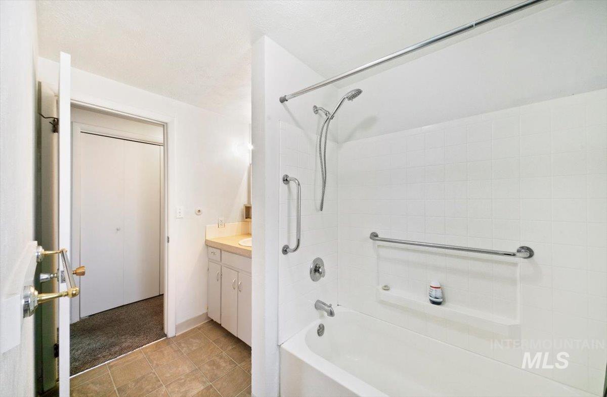 Full bath featuring shower / washtub combination, vanity, and light tile patterned floors