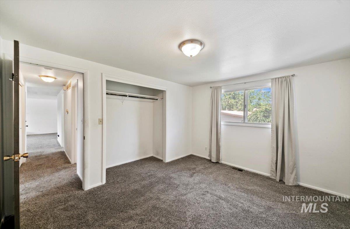 Unfurnished bedroom featuring dark colored carpet and a closet