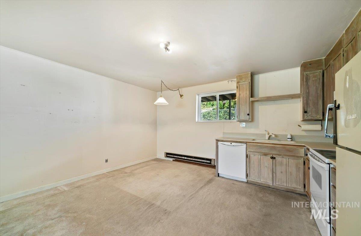 Kitchen with white appliances, light countertops, open shelves, light brown cabinets, and a baseboard radiator